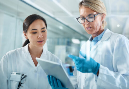 two female clinical researchers looking at a tablet in lab